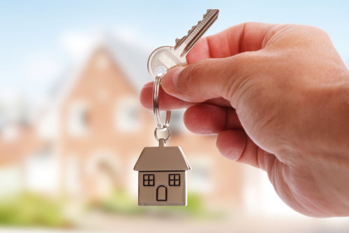 man's hand holidng a key with a house key chain