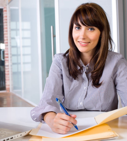 Business Woman Writing notes at desk in a modern office